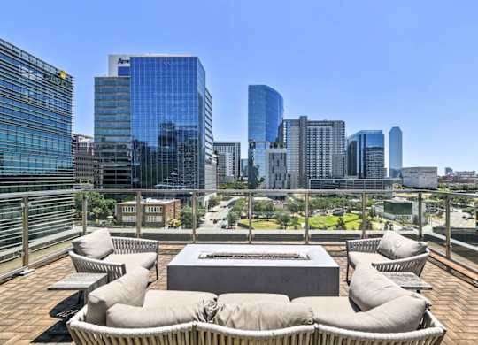 A rooftop patio with a table and chairs overlooking a city skyline.