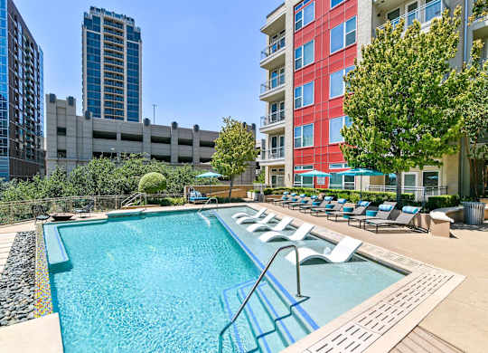 A swimming pool with a metal ladder and lounge chairs.