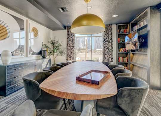 A modern dining room with a round wooden table and grey chairs.