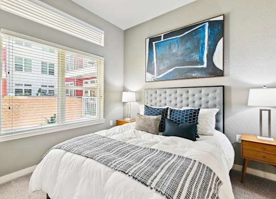 A bedroom with a large bed and a painting on the wall.
