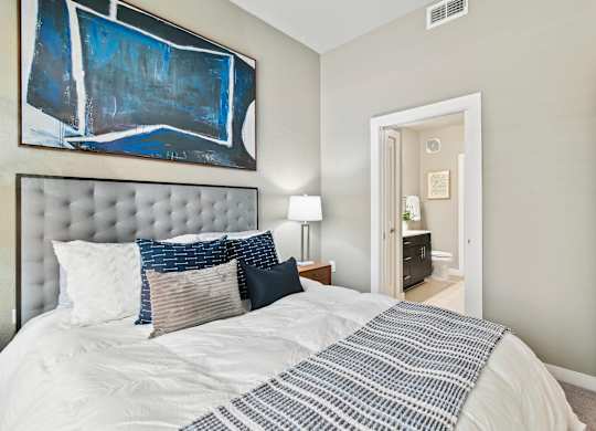 A bedroom with a large bed and a painting on the wall.