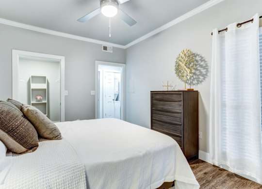 A bedroom with a bed, dresser, and a ceiling fan.