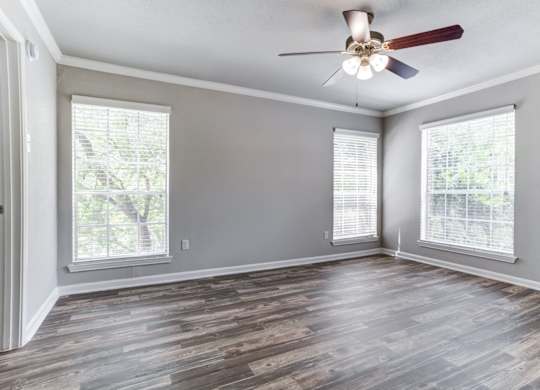 A room with a ceiling fan and wooden flooring.