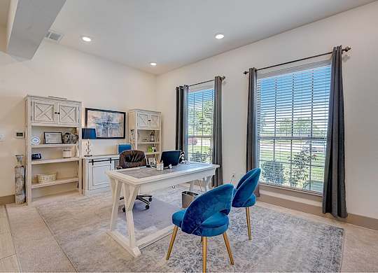 A room with a desk and blue chairs.