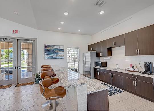 A kitchen with a marble countertop and a view of the outdoors through the window.