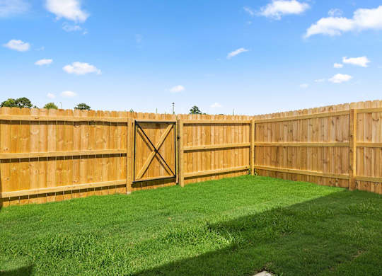a wooden fence in a backyard with grass