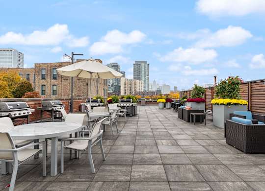 A rooftop patio with tables and chairs overlooking a city skyline.