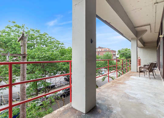 A balcony with a red railing and a view of a street below.
