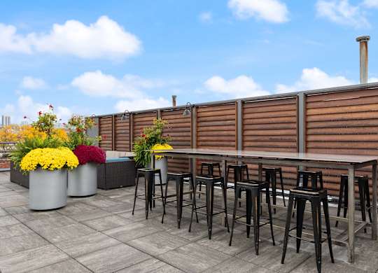 A patio with a table and chairs and flower pots.