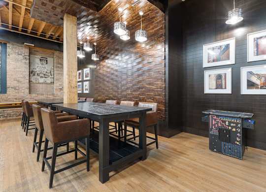 A room with a long table and chairs and a pinball machine.