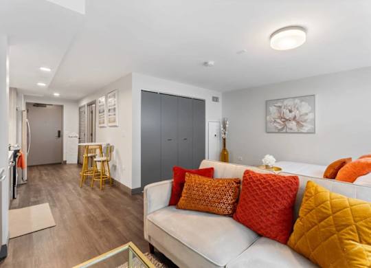 A living room with a white couch and orange pillows.