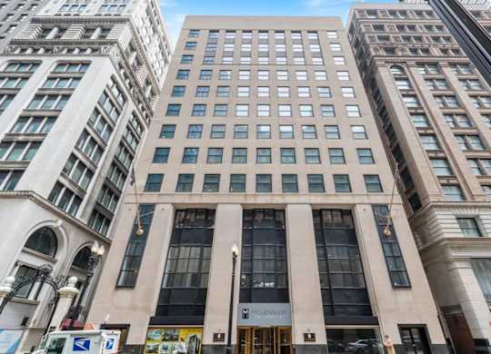 The building in the image is a tall, beige, rectangular structure with a large entrance and a sign that reads "HILLEN".