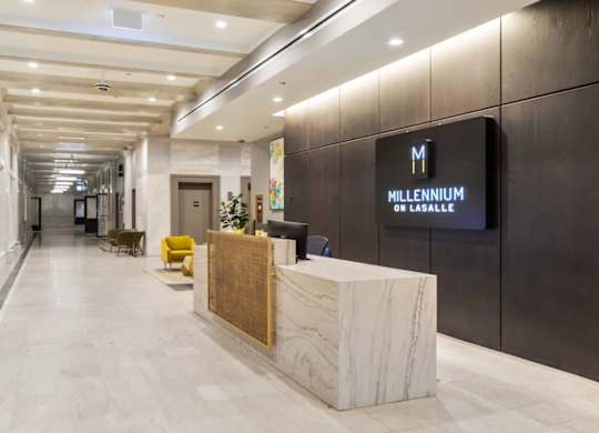 A reception area with a marble counter and a sign that says "Millennium on Lasalle".