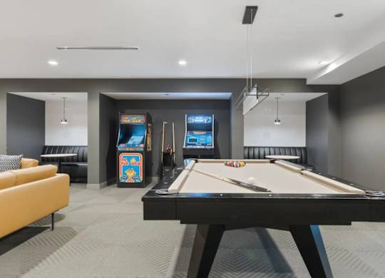 A room with a pool table and arcade games.