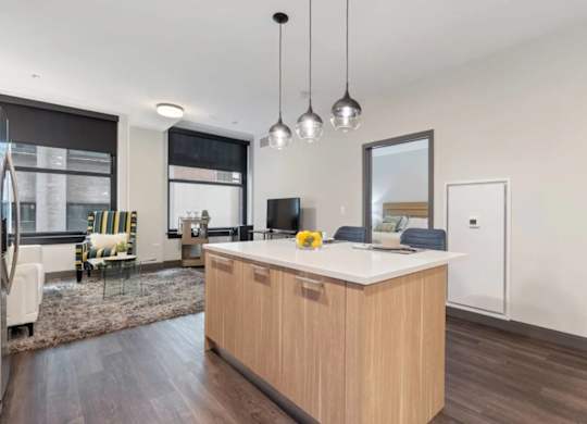 A modern kitchen with a wooden island and pendant lights.