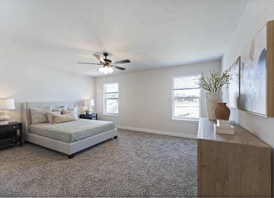 A bedroom with a bed, nightstand, and a ceiling fan.