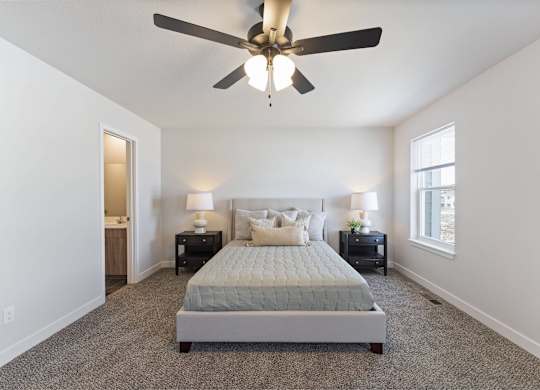 A bedroom with a bed, two nightstands, and a ceiling fan.