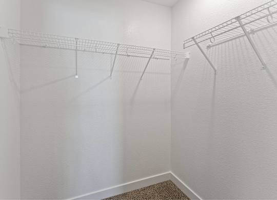 A white closet with a carpeted floor and two racks of clothes.