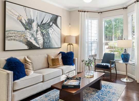 A living room with a white couch, a coffee table, and a painting on the wall.