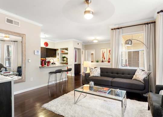 A living room with a grey couch and a glass coffee table.