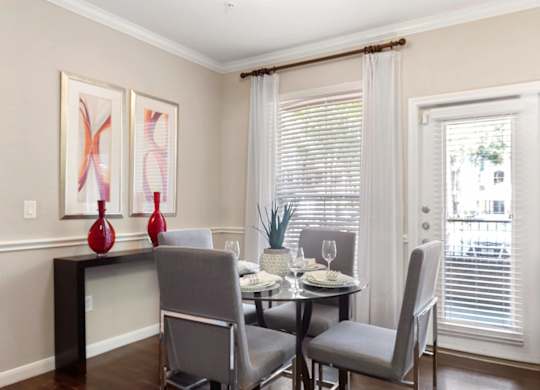 A dining room with a table set for two and two chairs.