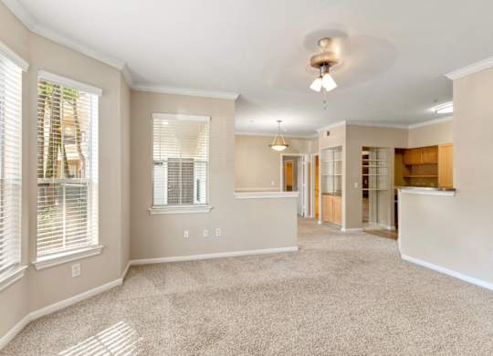 A spacious living room with a carpeted floor and a ceiling fan.