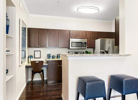 A kitchen with a white counter and blue stools.