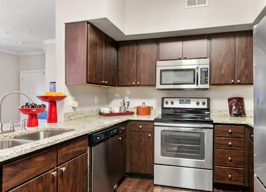 A modern kitchen with dark wood cabinets and stainless steel appliances.