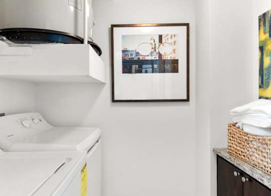 A white washing machine is on top of a dryer in a small laundry room.
