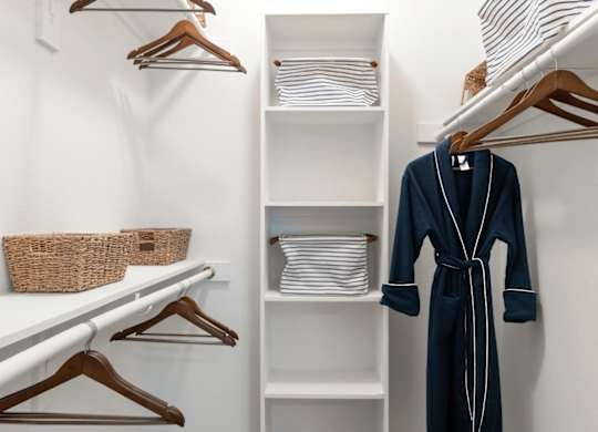 A white closet with a blue robe hanging on a hanger.