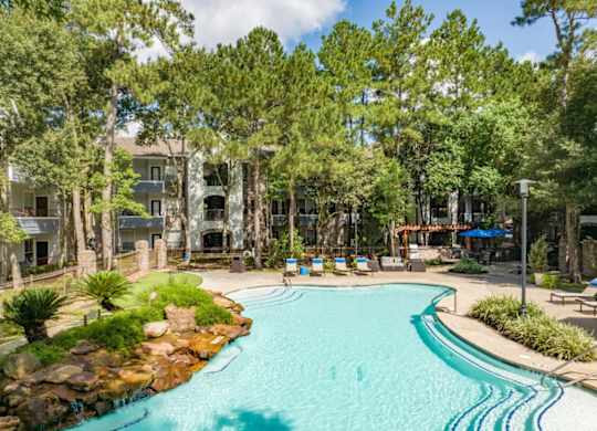 A swimming pool surrounded by trees and a building in the background.
