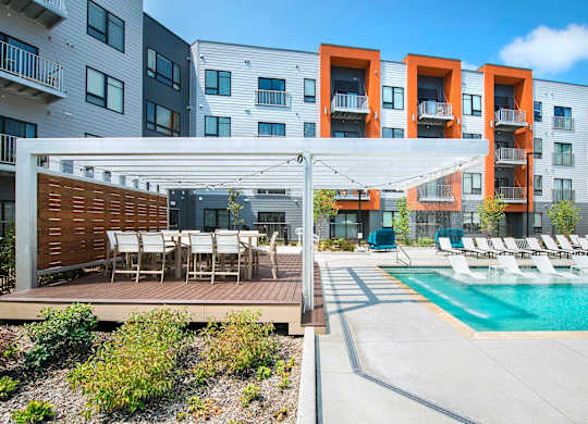 A modern apartment complex with a pool and outdoor seating area.