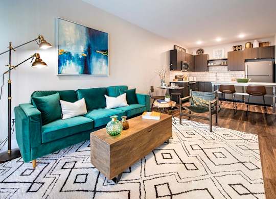 Luxury Apartments in Berkley Riverfront, MO, with In-Unit Washer and Dryer - Union Berkley - Living Room with Wood-Style Flooring, Area Rug, Sofa, Wooden Chest Coffee Table, Armchair, and Floor Lamp.