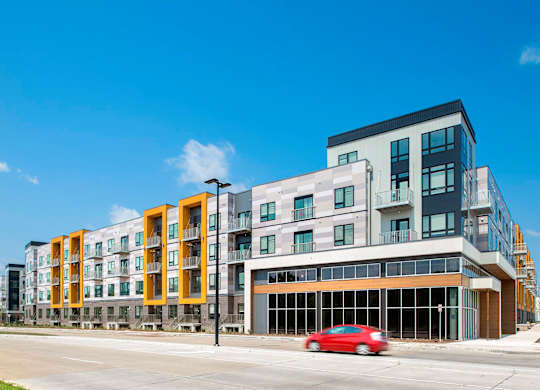 A red car is parked in front of a modern building.
