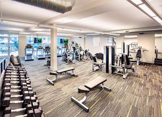 A gym with a variety of equipment including weights and benches.