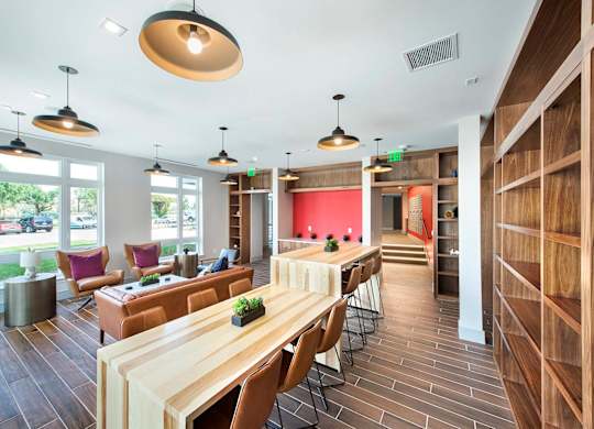A long wooden table is surrounded by chairs in a room with a red wall.