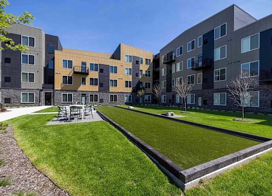 A modern apartment complex with a grassy courtyard in the foreground.