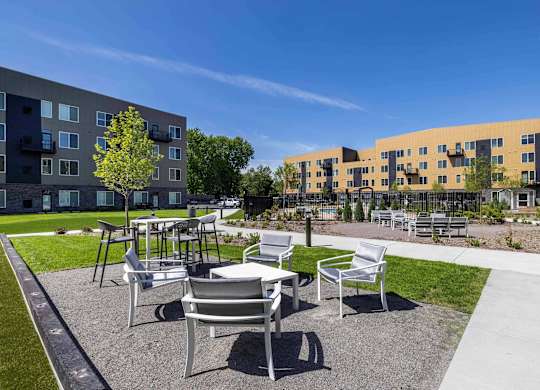 A sunny day at a modern apartment complex with a seating area in the foreground.