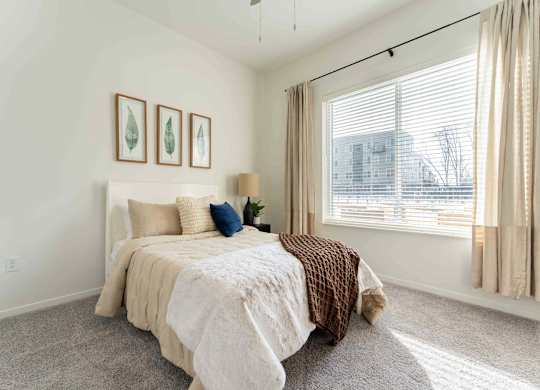 A bedroom with a bed, pillows, and pictures on the wall.