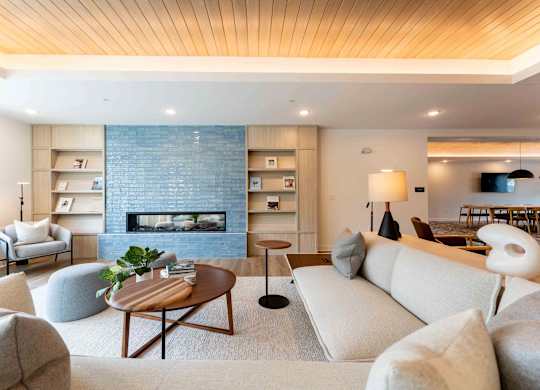 A modern living room with a fireplace and a wooden ceiling.