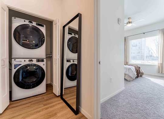 A laundry room with two washing machines and a mirror.