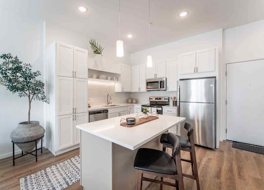A kitchen with a white table and black chairs.