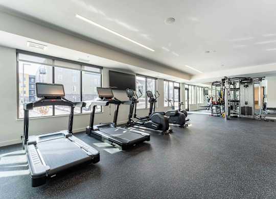 A gym with treadmills, elliptical machines, and other exercise equipment.