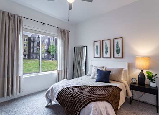 A bedroom with a large bed and a window overlooking a green area.