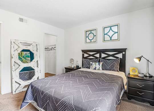 A bedroom with a bed, nightstand, and lamp.