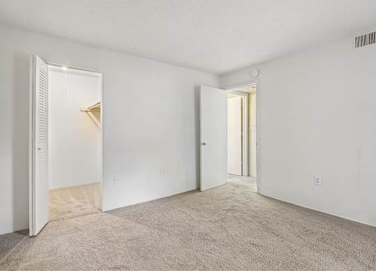 A room with carpeted floor and two open doors.