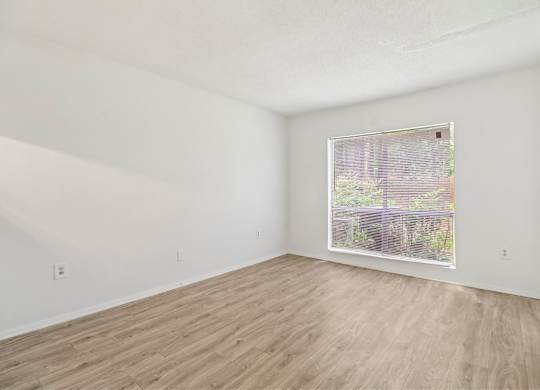 Empty room with wooden flooring and a window.