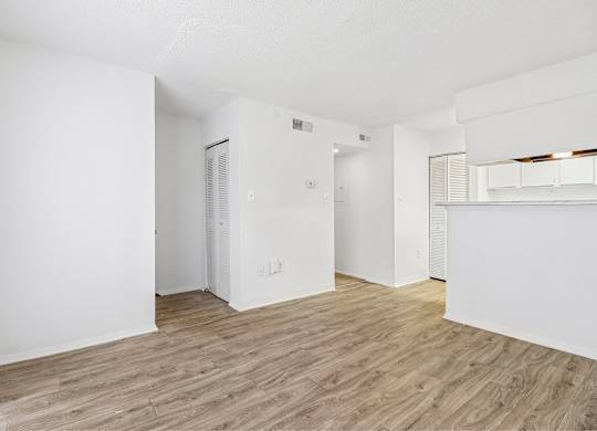 A spacious room with wooden flooring and white walls.