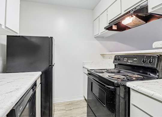 A black refrigerator is on the left and a black oven is on the right in a kitchen.