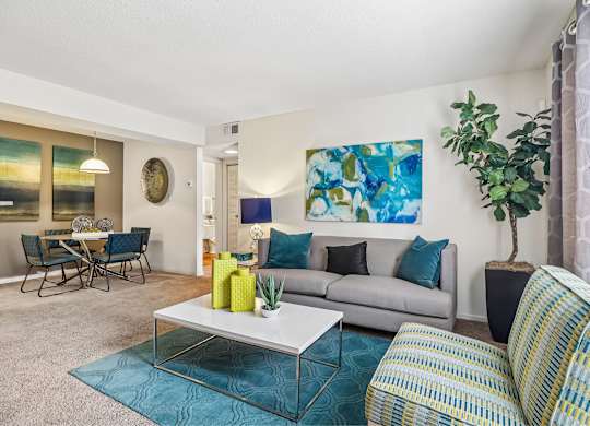A living room with a grey couch, a coffee table, and a painting on the wall.